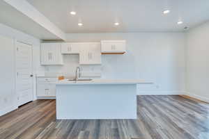 Kitchen with hardwood / wood-style flooring, sink, an island with sink, and white cabinets