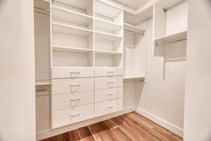 Walk in closet with light hardwood / wood-style flooring