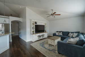 Living room featuring ceiling fan, dark hardwood / wood-style flooring, and vaulted ceiling