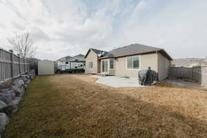 Back of property with a yard, a patio area, and a storage unit