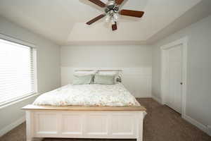 Carpeted bedroom with ceiling fan and a raised ceiling