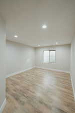 Empty room with a textured ceiling and light wood-type flooring