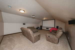 Carpeted home theater room with lofted ceiling