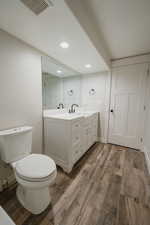 Bathroom with hardwood / wood-style flooring, vanity, and toilet