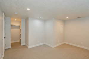 Basement featuring light colored carpet and a textured ceiling