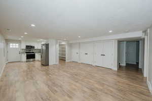 Unfurnished living room featuring a textured ceiling and light hardwood / wood-style flooring