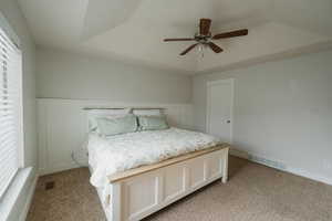 Unfurnished bedroom featuring ceiling fan, a tray ceiling, and light carpet