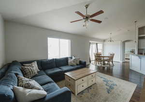 Living room with ceiling fan, dark hardwood / wood-style flooring, and vaulted ceiling