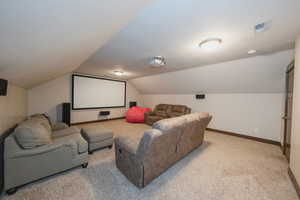 Carpeted home theater room featuring lofted ceiling