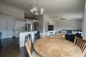 Dining space featuring lofted ceiling, sink, ceiling fan with notable chandelier, and dark hardwood / wood-style flooring