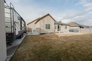 Rear view of property with a lawn and a patio