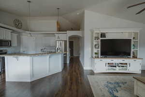 Kitchen with pendant lighting, white cabinets, a large island with sink, light stone counters, and stainless steel appliances