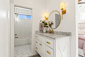 Full bathroom with tile patterned floors, vanity, toilet, and tiled shower / bath combo