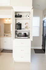 Kitchen with light tile patterned flooring, lofted ceiling, sink, and white cabinets