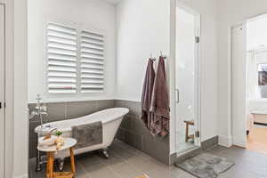 Bathroom with independent shower and bath, tile walls, and tile patterned floors