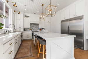 Kitchen featuring sink, white cabinetry, decorative light fixtures, a kitchen island, and stainless steel appliances