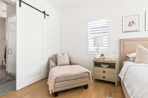 Bedroom featuring crown molding, a barn door, and light wood-type flooring