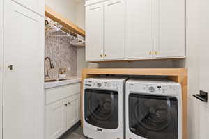 Washroom with cabinets, sink, dark tile patterned flooring, and washer and clothes dryer