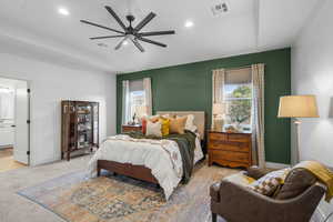 Carpeted bedroom featuring ceiling fan, connected bathroom, and vaulted ceiling