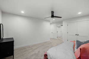 Carpeted bedroom with ceiling fan and a closet