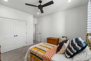 Bedroom featuring light colored carpet, ceiling fan, and a closet