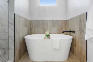 Bathroom featuring a washtub and tile walls