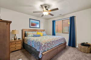 Carpeted bedroom with ceiling fan and a textured ceiling