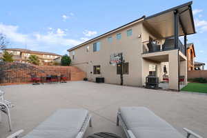 Rear view of property with cooling unit, a patio area, and a balcony