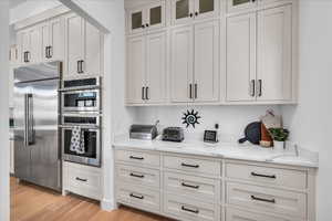 Kitchen with light stone counters, stainless steel appliances, light hardwood / wood-style floors, and white cabinets