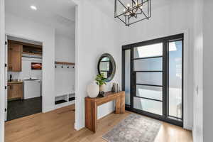 Foyer featuring an inviting chandelier, washer and clothes dryer, and light hardwood / wood-style floors