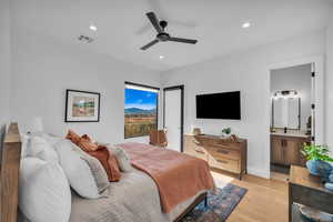 Bedroom with ceiling fan, ensuite bath, and light wood-type flooring