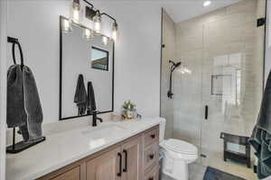 Bathroom with vanity, walk in shower, tile patterned floors, and toilet