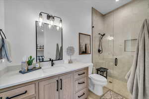 Bathroom featuring vanity, tile patterned floors, a shower with door, and toilet