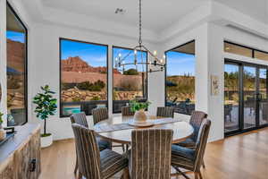 Dining room with a chandelier, a tray ceiling, a mountain view, and light hardwood / wood-style floors