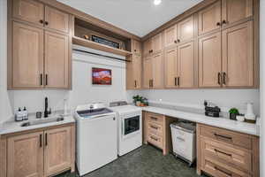 Washroom with sink, cabinets, washing machine and clothes dryer, and dark tile patterned flooring