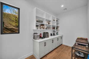 Interior space featuring white cabinetry, light stone countertops, and light wood-type flooring