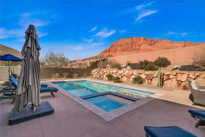 View of pool with an in ground hot tub, a mountain view, and a patio