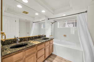 Bathroom featuring shower / tub combo with curtain, vanity, a tray ceiling, and hardwood / wood-style floors