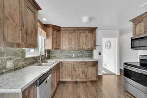 Kitchen featuring sink, decorative backsplash, dark wood-type flooring, and stainless steel appliances