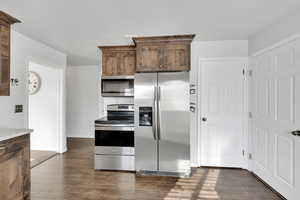 Kitchen featuring dark wood-type flooring and appliances with stainless steel finishes