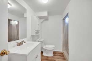 Bathroom featuring hardwood / wood-style flooring, vanity, toilet, and walk in shower