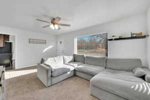 Carpeted living room featuring ceiling fan