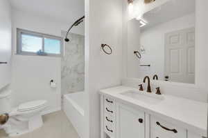 Full bathroom featuring vanity, tiled shower / bath combo, and toilet