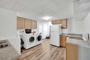 Laundry room featuring sink, light hardwood / wood-style flooring, and washer and dryer