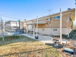 Rear view of property with an outdoor fire pit, a patio, a trampoline, and a lawn