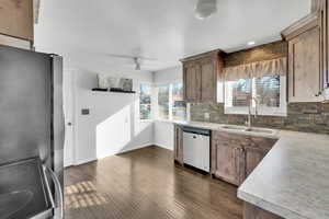 Kitchen with sink, ceiling fan, appliances with stainless steel finishes, backsplash, and dark hardwood / wood-style floors