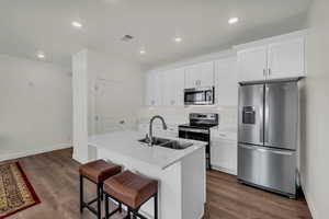 Kitchen featuring appliances with stainless steel finishes, a kitchen island with sink, sink, and white cabinets