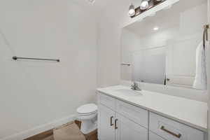 Bathroom with wood-type flooring, toilet, vanity, and a shower