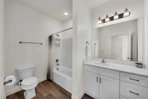 Full bathroom featuring wood-type flooring, toilet, shower / bath combo with shower curtain, and vanity