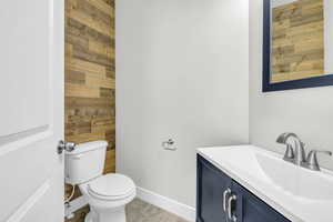 Bathroom with vanity, toilet, and wood walls